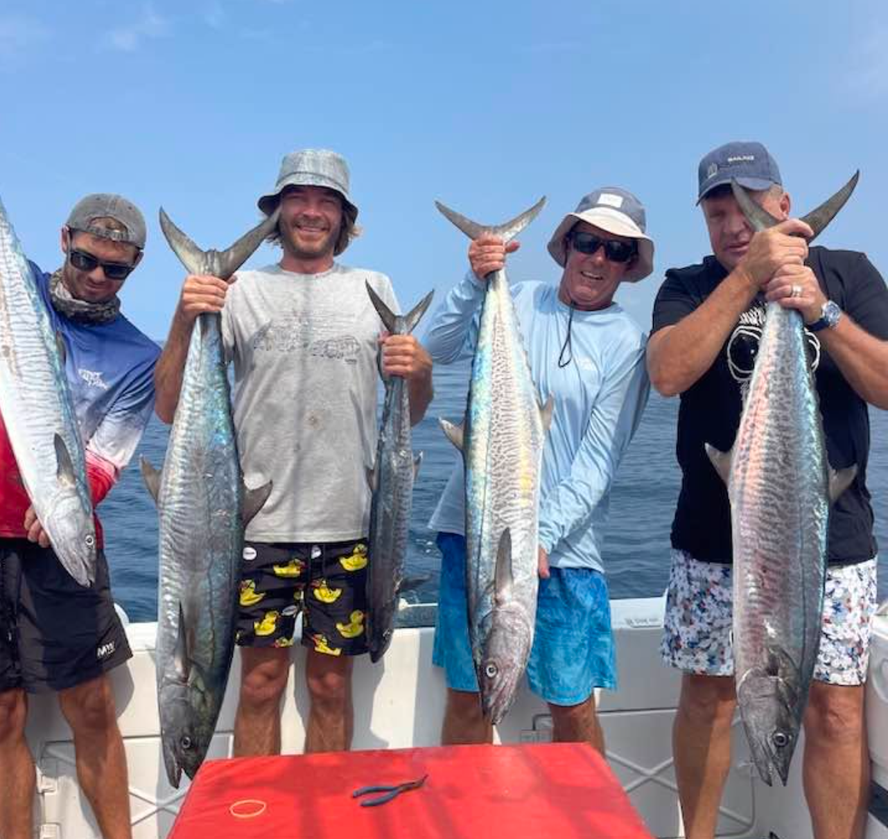 A group of guests proudly holding their catch on a Bemugi's fishing trip