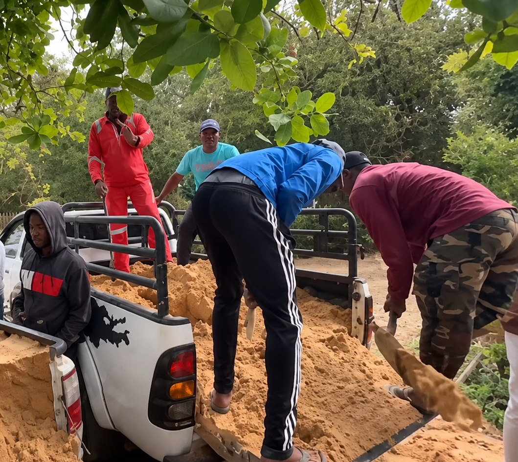 Team members unloading sand from a truck as part of the rebuild at Bemugi's Place