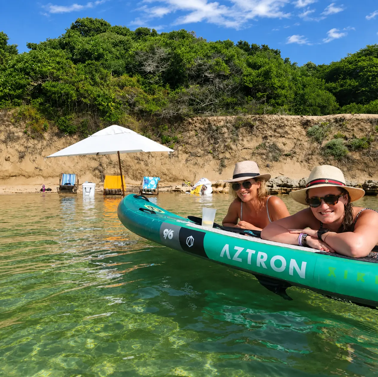 Guests relaxing on a paddleboard in the calm, clear shallows at Bemugi's