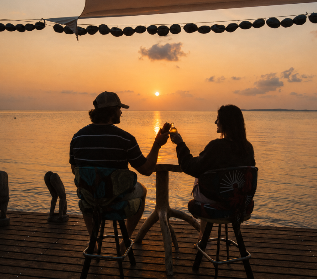 Two guests toasting drinks on the Bemugi's sunset deck as the sun sets over Maputo Bay