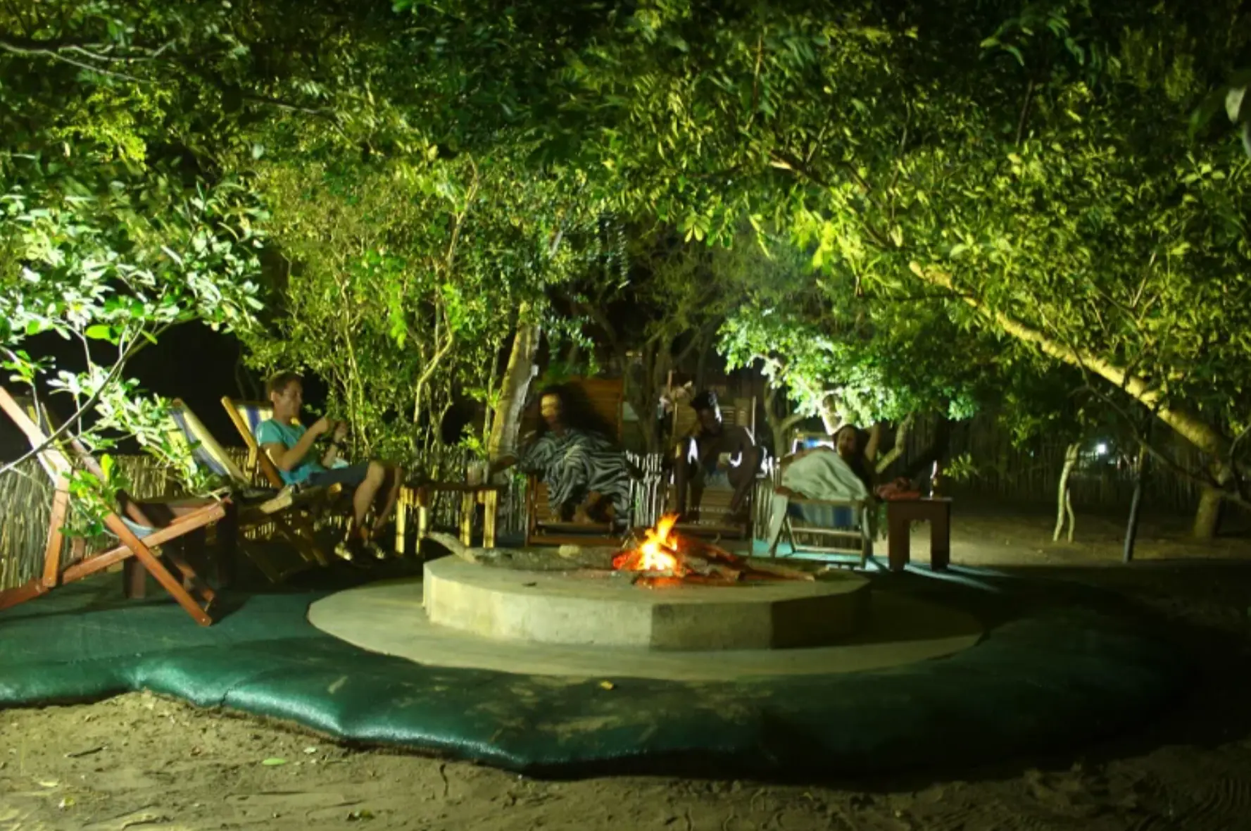 Evening braai fire with guests relaxing in deck chairs