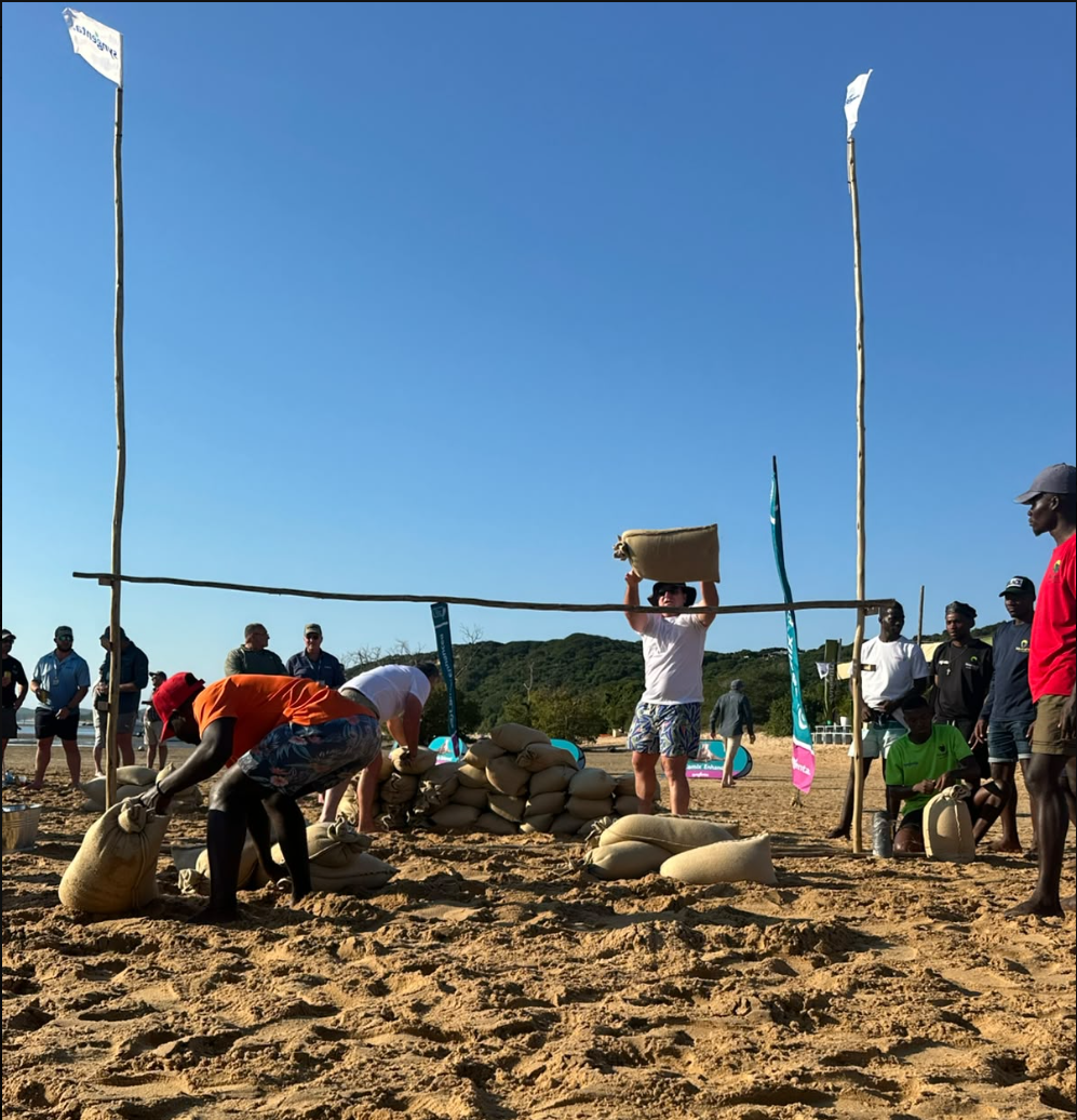 Teams competing in a beach challenge with sandbags on the sand at Bemugi's