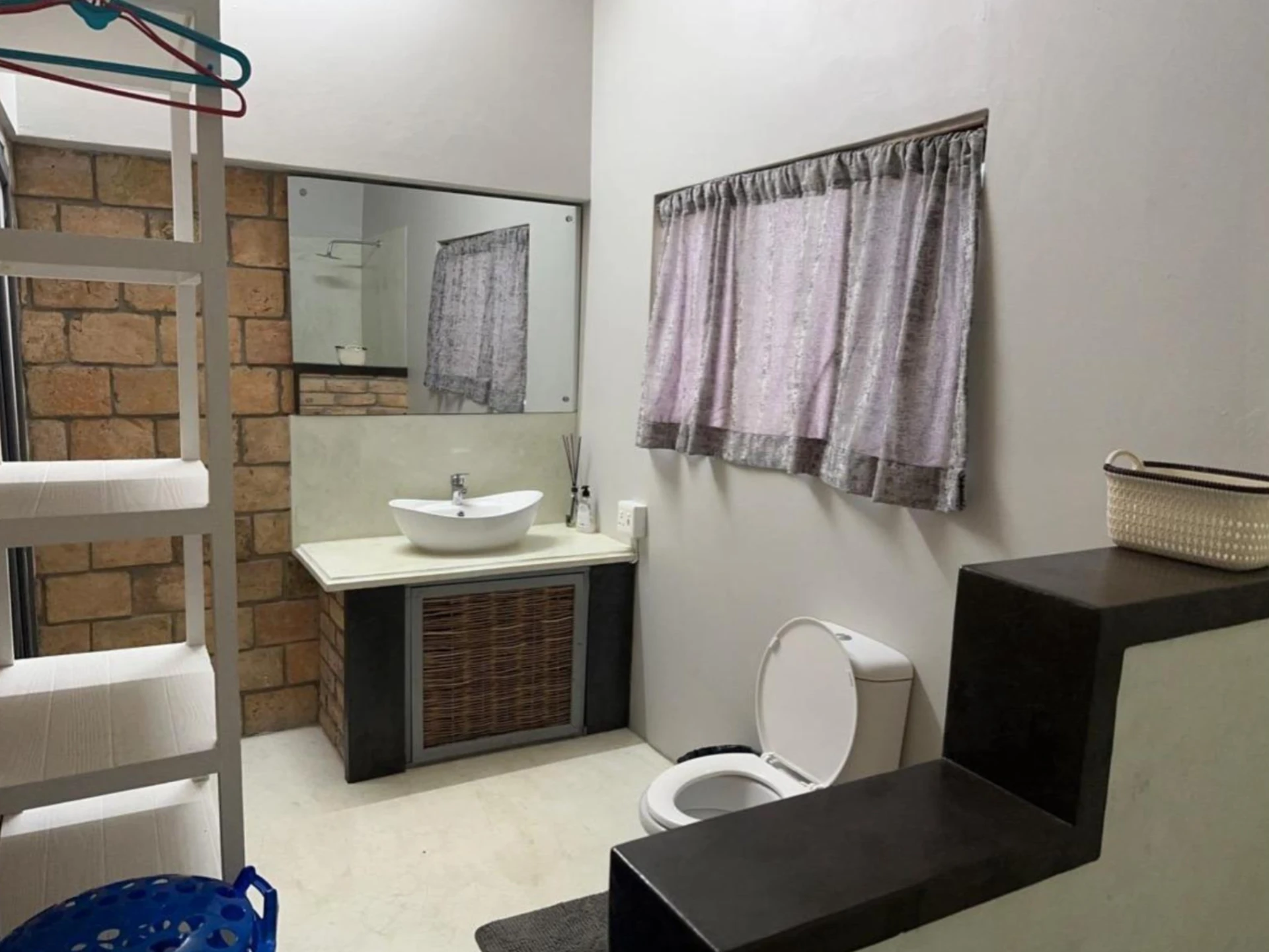 En-suite bathroom with basin, toilet and exposed brick