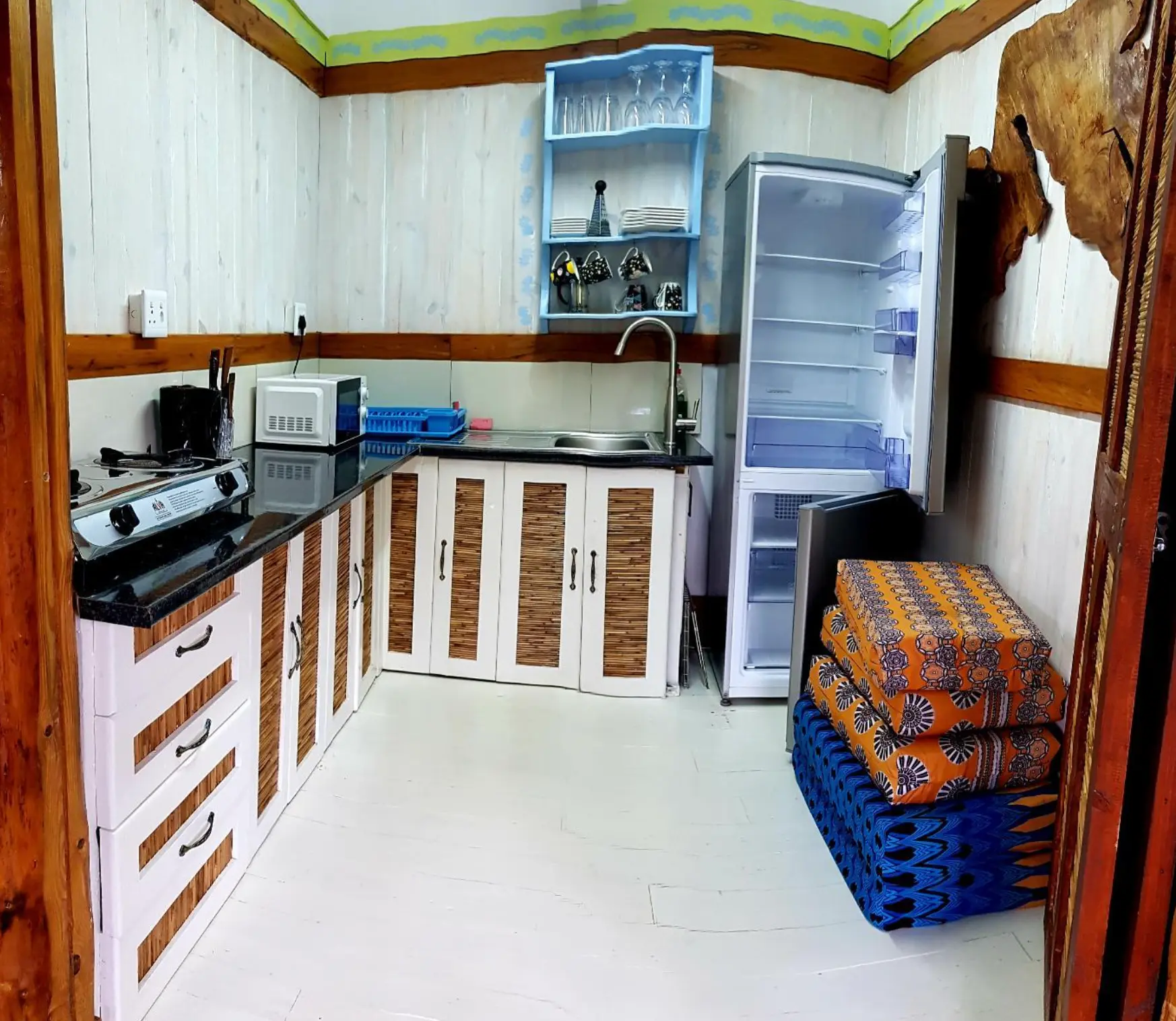 Kitchen with counter, microwave, open fridge and storage bench