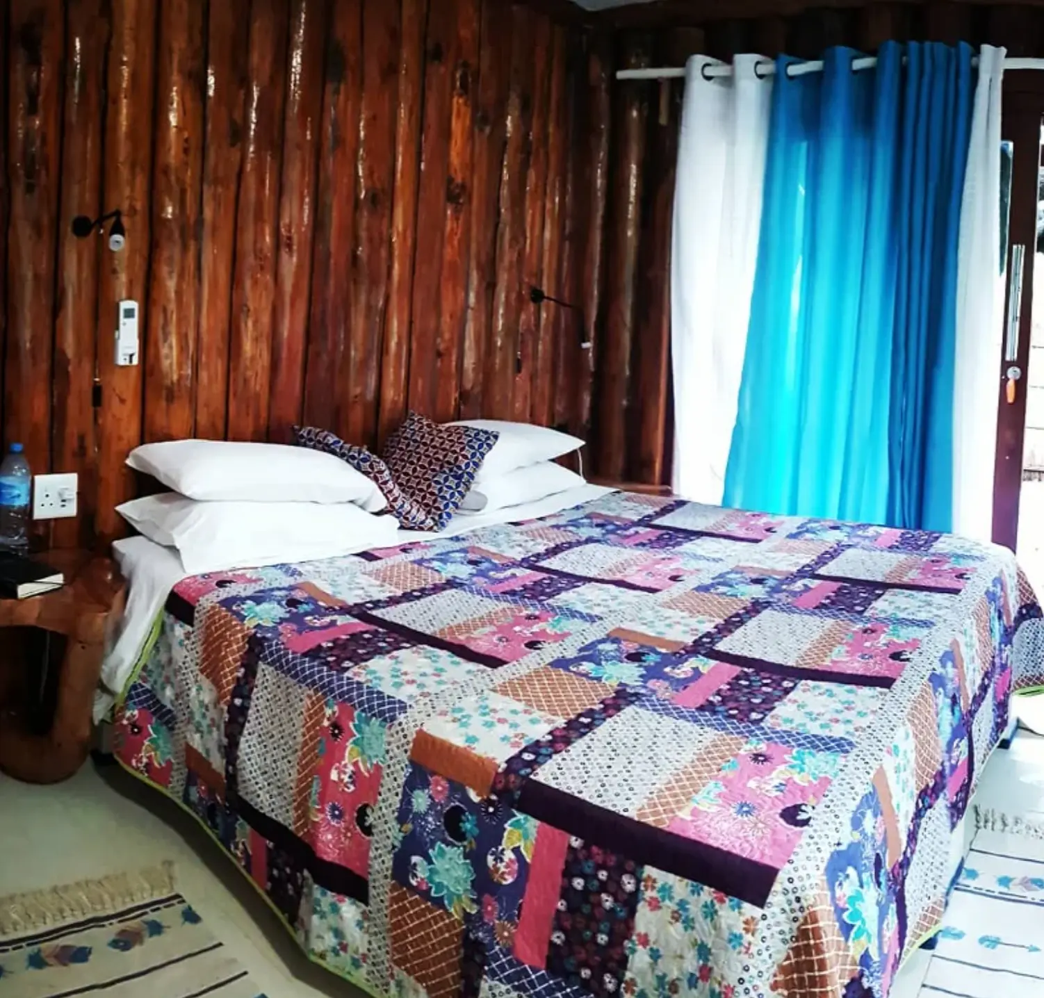 Bedroom with wooden walls and colourful quilt
