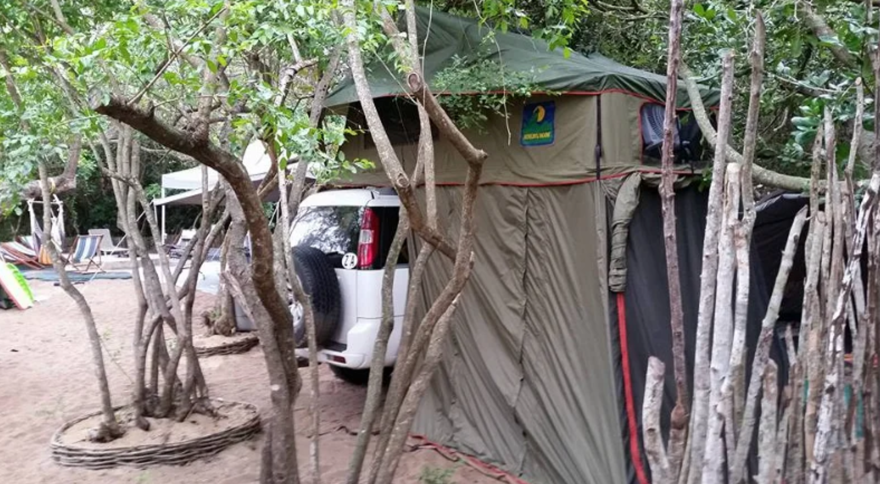 Rooftop tent with side awning room set up among the trees