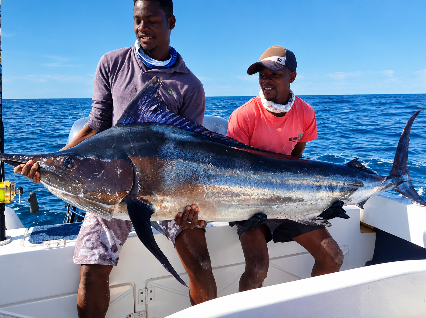 Two Bemugi's crew members holding a large marlin on a charter boat in the deep blue Indian Ocean