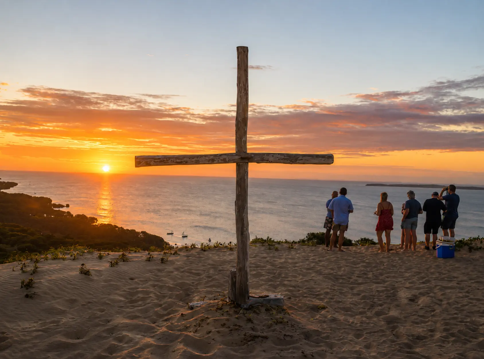A wooden cross on a high dune overlooking the sunset across Maputo Bay