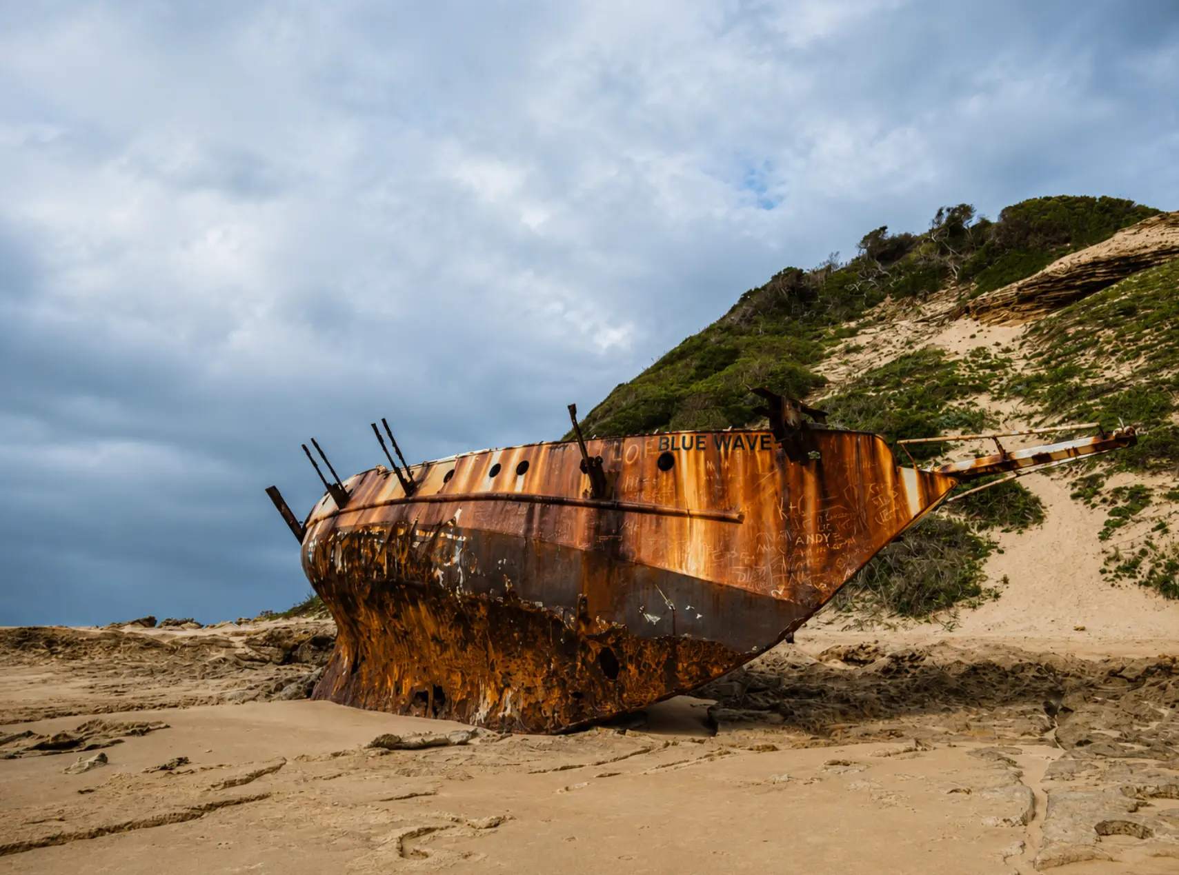 Rusted shipwreck of the Blue Wave resting on the sandy shore near Ponta Abril