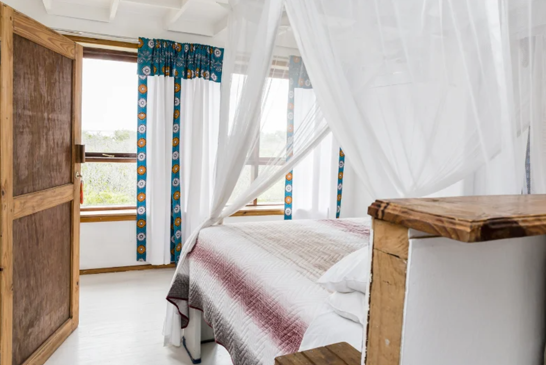 Bright bedroom with four-poster net and garden windows