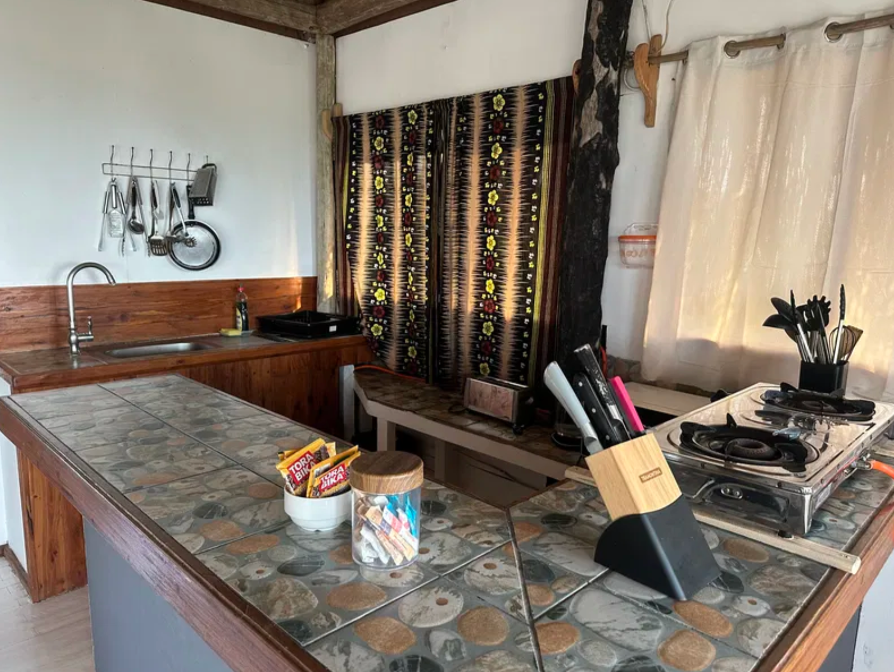 Kitchen counter with tiled island and patterned curtains