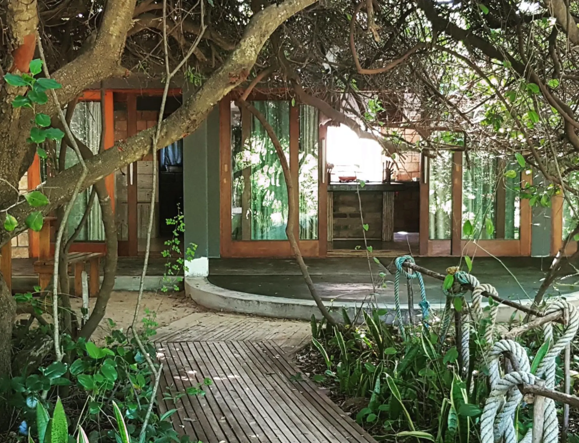 Wooden walkway leading to the house entrance through coastal trees