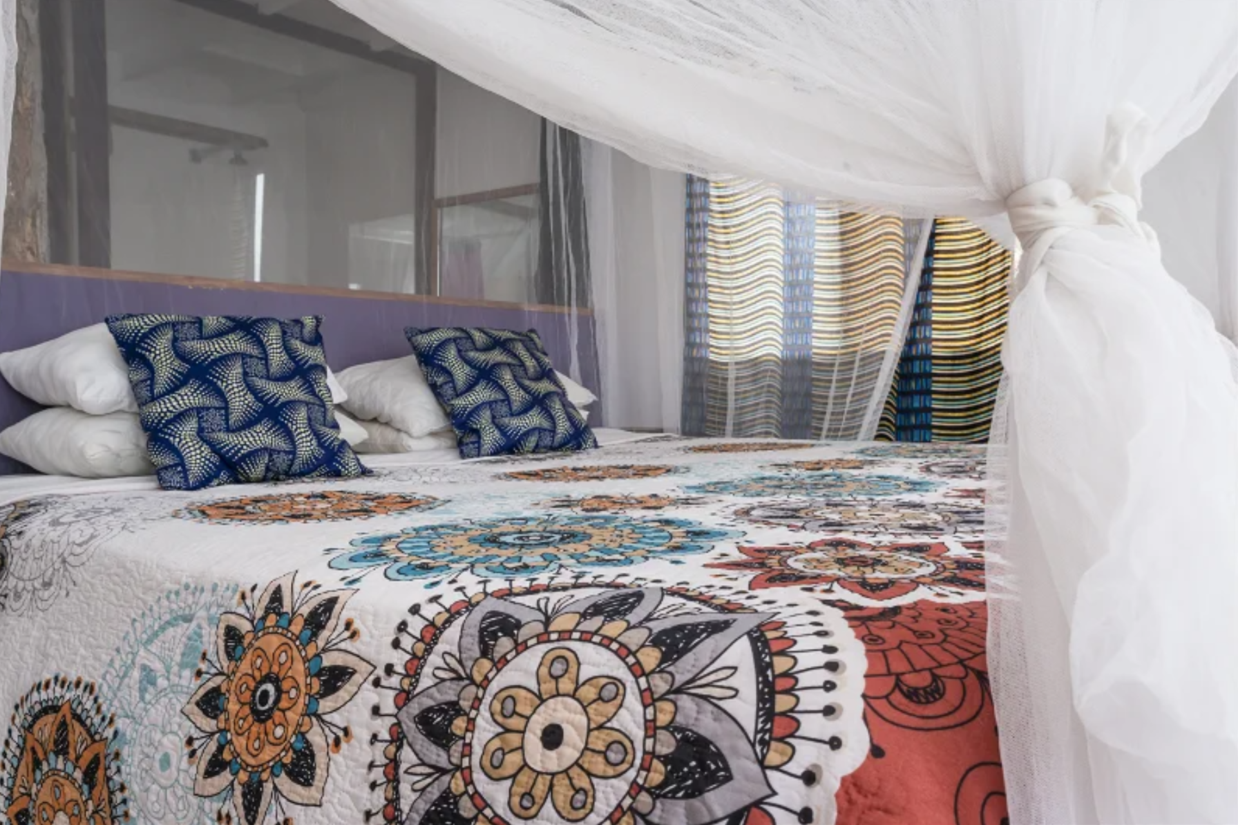 Bedroom with mandala quilt and printed cushions